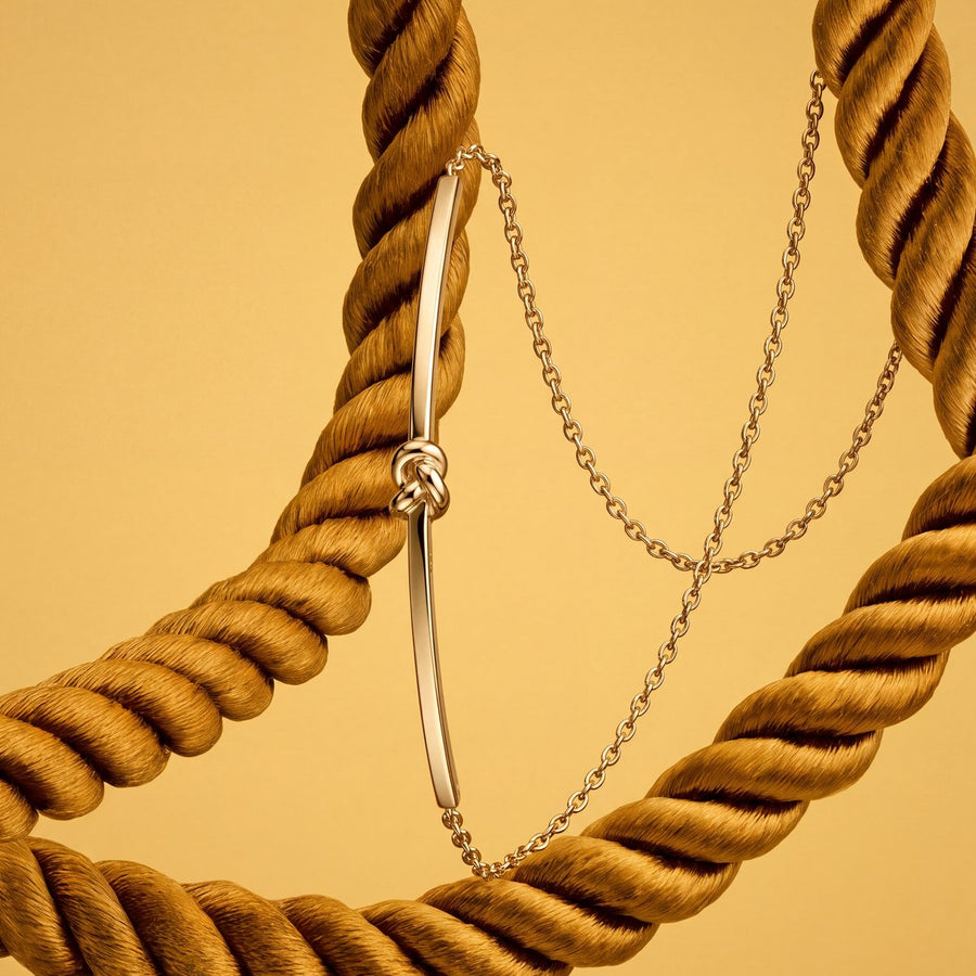 Gold knot bracelet against golden rope
