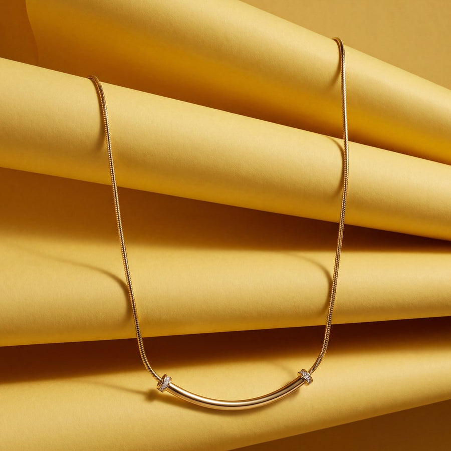 Gold necklace resting on folded yellow paper